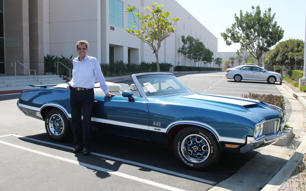 blue oldsmobile convertible with man
